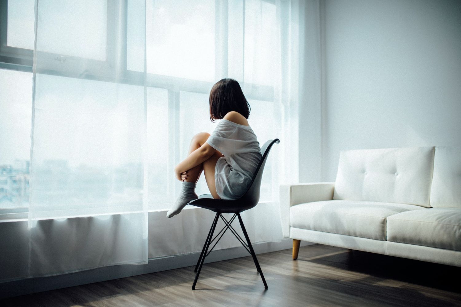 full length portrait of girl wearing shirt and denim shorts. sitting pose  on chair, isolated on grey studio background. Stock Photo | Adobe Stock