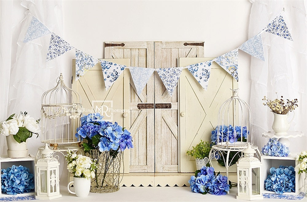 Fijne kunst met blauwe bloemen lichte bruine schuurdeur wit gordijnmuurachtergrond ontworpen door Mandy Ringe Fotografie