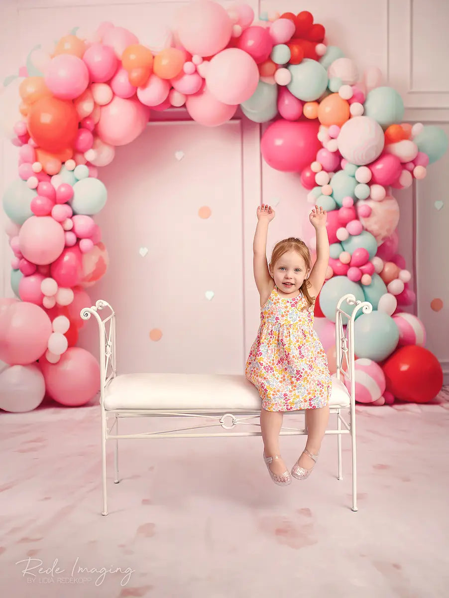 Explosión de pastel de cumpleaños en rosa suave con pared de líneas, arco de globos coloridos y confeti diseñado por Lidia Redekopp