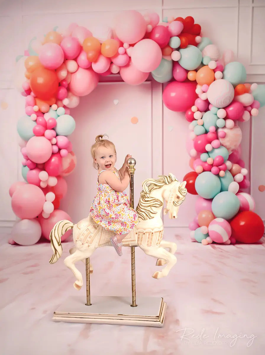 Explosión de pastel de cumpleaños en rosa suave con pared de líneas, arco de globos coloridos y confeti diseñado por Lidia Redekopp